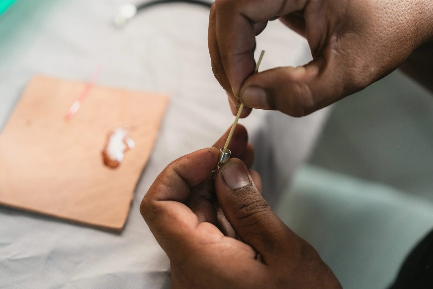 Artisan threading a leather cord into a silver clasp fitting at a workbench in Bali