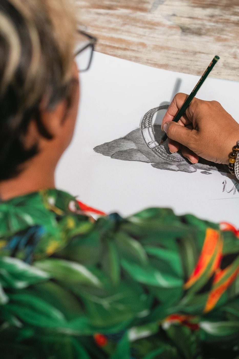 Designer sketching a custom leather bracelet in pencil at the MANQ workshop