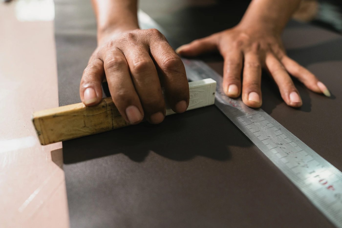 Creasing the edge of a leather strap with a wooden tool and steel ruler